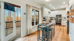 A modern kitchen with white cabinets, a central island, and a dining area with bar stools.
