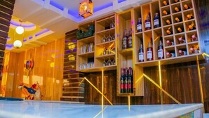 A bar area with shelves of bottles and glasses, wooden decor, and a pool table. - LINKS HOTEL  (Owerri)