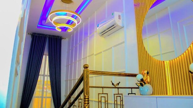 A modern interior with a staircase, a circular mirror, and a decorative sculpture. - LINKS HOTEL  (Owerri)