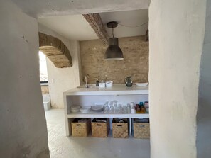 A kitchen with a white countertop, a hanging light fixture, and storage bins below.