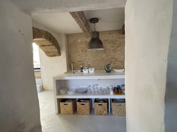 Una cocina con encimera blanca, lámpara colgante y contenedores de almacenamiento debajo.