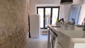 Une petite cuisine comprenant un lave-linge, un réfrigérateur et un évier.
