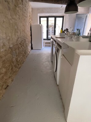 A narrow kitchen with a washing machine, a refrigerator, and a sink.