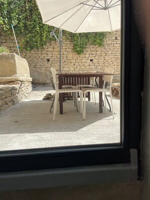 A patio with a table and chairs, an umbrella, and a stone wall. - Gordes, in the heart of the village with private pool and panoramic view (Gordes)