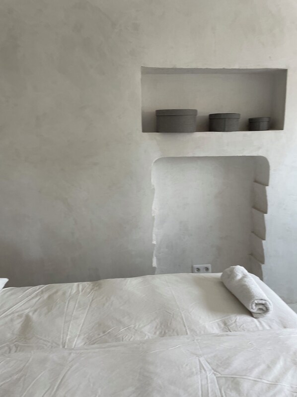 Une chambre à coucher avec un lit, une étagère fixée au mur avec des compartiments et une niche intégrée.