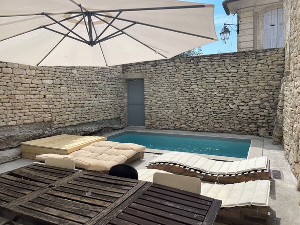 A stone-walled outdoor area with a pool, lounge chairs, and an umbrella. - Gordes, in the heart of the village with private pool and panoramic view (Gordes)