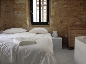 A bedroom with a bed, bedside table, and a wooden dresser.