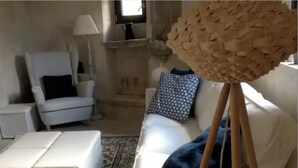 Una sala de estar con un sofá blanco, un sillón blanco, una mesita pequeña blanca y una lámpara.