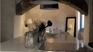 Una cocina con un arco de piedra, encimera de acero inoxidable, una lámpara colgante y vistas al exterior.