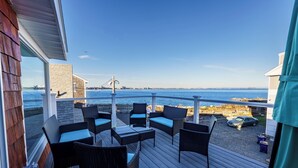 Eine Terrasse mit Gartenmöbeln mit Blick auf das Wasser.