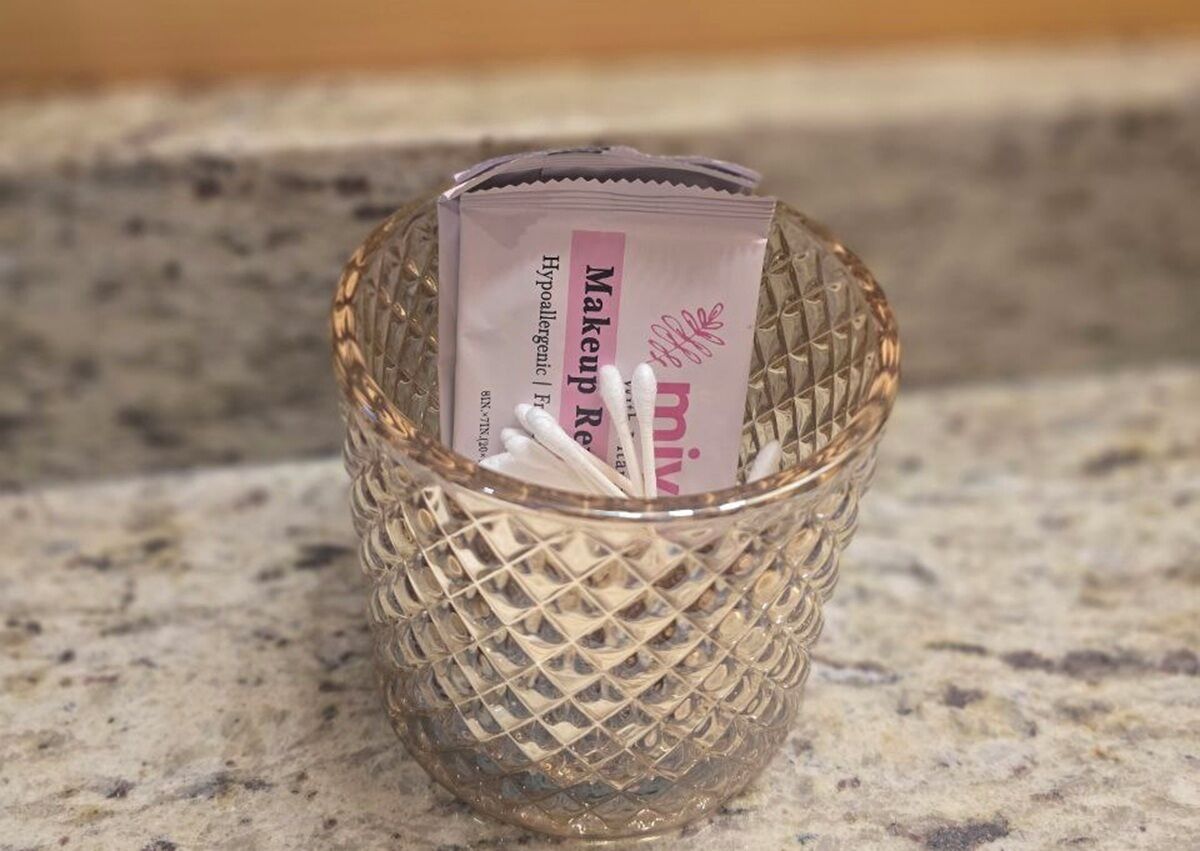 A glass container with a makeup product labeled "Makeup Revive" on a granite countertop.