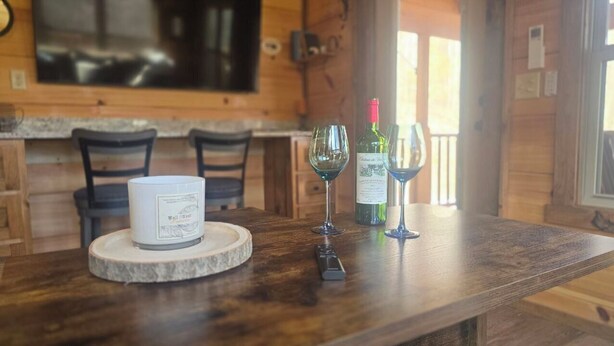 Un intérieur en bois avec une table en marbre, deux verres à vin et une bougie.