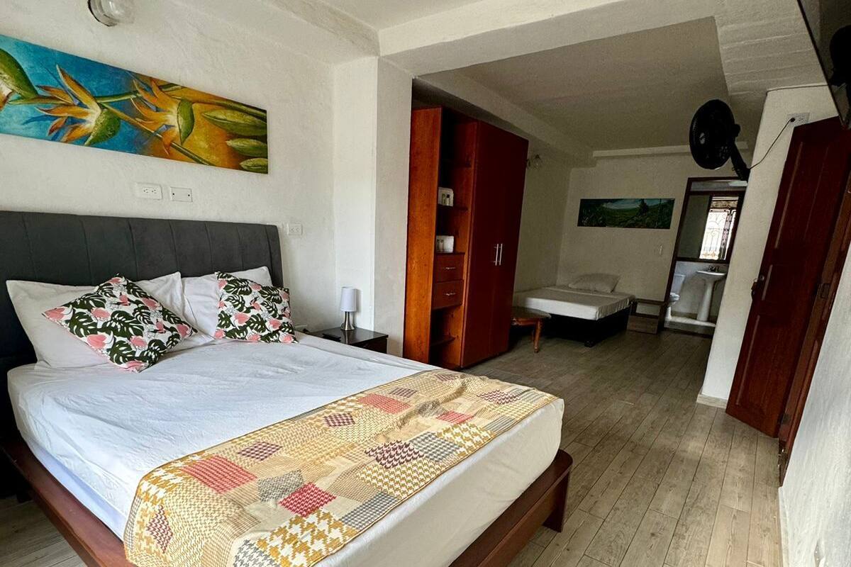 A bedroom with a wooden bed, a nightstand, a wardrobe, and a bathroom visible through an open door.
