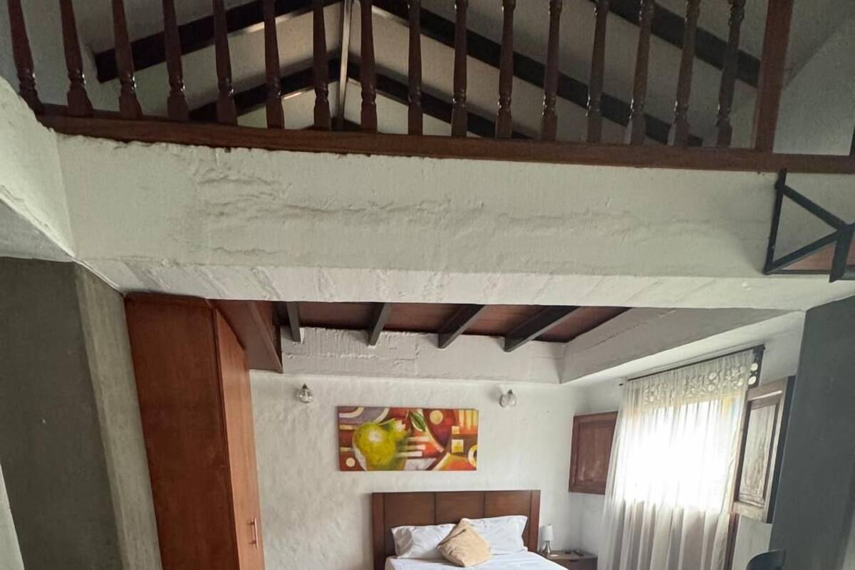 A bedroom with a bed, a wooden bench, a small table, and a painting on the wall.