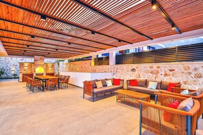 An outdoor seating area with wooden furniture and a stone wall backdrop. - Villa Overseas Views (Unknown)