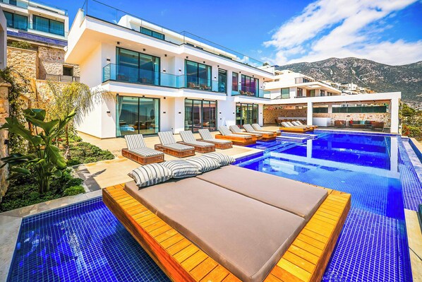 A modern villa with a pool, lounge chairs, and a mountain view. - Villa Overseas Views (Unknown)