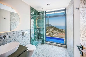 A modern bathroom with a large window, a sink, and a toilet. - Villa Overseas Views (Unknown)