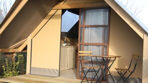 Une petite cabane en bois dotée d’un balcon, d’une table pliante et de deux chaises.