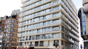 Un hotel de varios pisos con balcones en cada planta, una entrada a nivel de calle y un letrero visible que dice 'ABITA'.