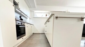 Una cocina moderna con armarios blancos, horno integrado y ventana sobre el fregadero.