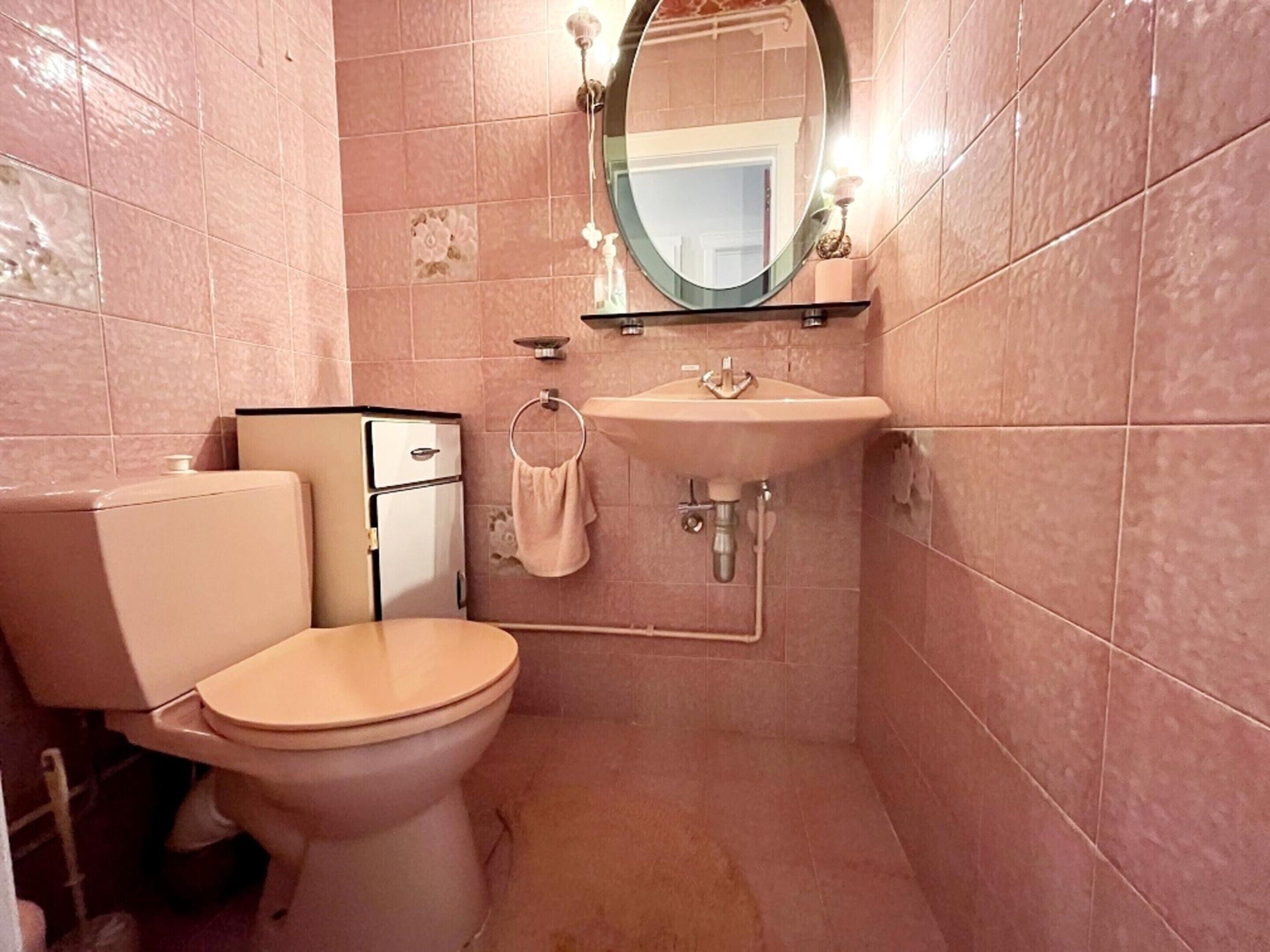 Ein kleines Badezimmer mit Toilette, Waschbecken und Spiegel.