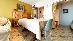 A dining area with a table set for two, a wooden cabinet with drawers, and a patterned floor. - Apartment in Wenduine With Stunning Sea View (De Haan)