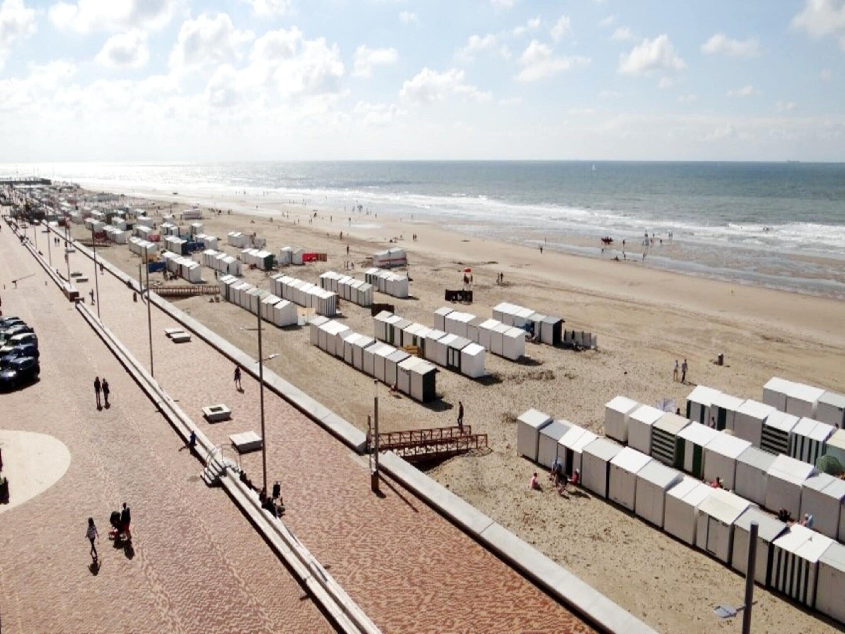 Una playa con cabañas portátiles y un paseo marítimo de arena.