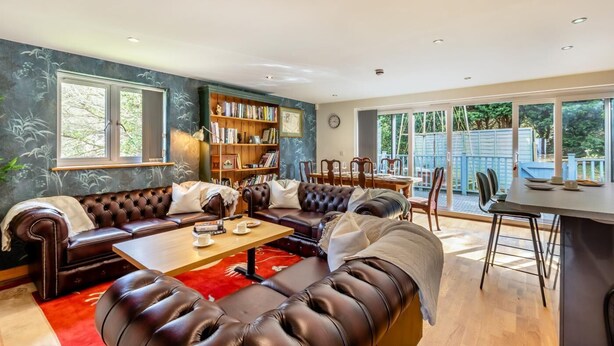A spacious living room with a leather sofa, a coffee table, and a bookshelf. - 2 Bed in West Quantoxhead (oc-p30893) (West Quantoxhead)