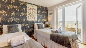 A hotel room with two beds, a large window, and a wall with a leaf pattern. - 2 Bed in West Quantoxhead (oc-p30893) (West Quantoxhead)