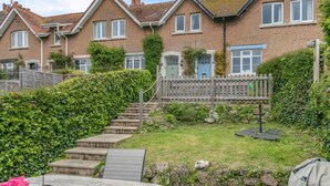 A residential area with a wooden staircase leading to a house with a blue door, surrounded by greenery and a small garden. - 3 Bed in Beer (oc-b31132) (Beer)