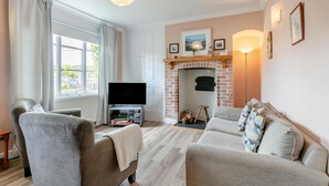 A living room with a fireplace, a TV, and a sofa. - 3 Bed in Beer (oc-b31132) (Beer)