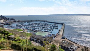 A marina with numerous boats docked, a pier extending into the water, and a building with a green roof in the foreground. - 3 Bed in Torquay (oc-a31052) (Torquay)
