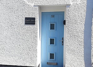 A blue door with the number 58, a white textured wall, and a sign reading 'Coastal Haven.'