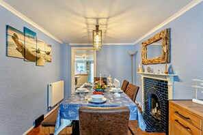 Un comedor con una mesa dispuesta para cuatro, una chimenea y decoración de temática náutica.
