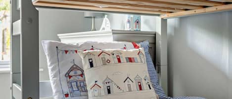 A bunk bed with a checkered bedspread and decorative pillows featuring maritime designs.