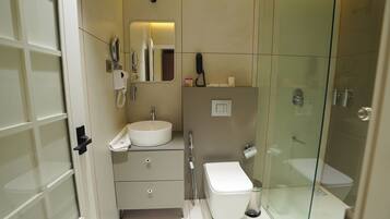A compact bathroom with a glass-enclosed shower, a white sink, and a toilet.