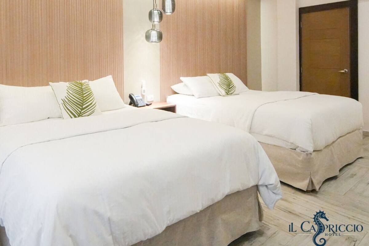 Habitación de hotel con dos camas, cabecero de madera, teléfono y el logotipo de Il Casuccio Hotel.