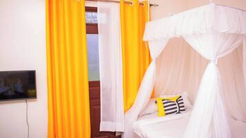 Un dormitorio con cama, televisor y cortinas.
