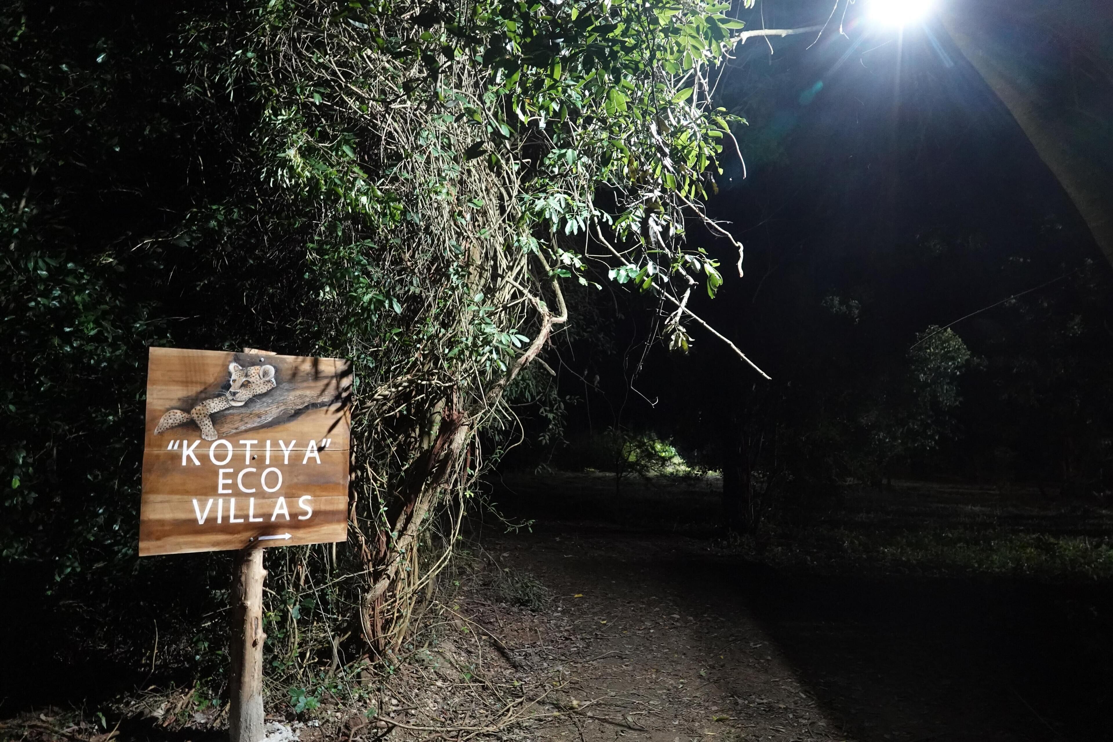 A wooden sign for "Kotiya Eco Villas" with a path leading through dense foliage.