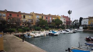 Un port de plaisance où sont amarrés des bateaux, entouré de bâtiments aux couleurs vives et de verdure.
