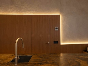A modern bathroom with a wooden vanity, a sink, and a frosted glass partition.