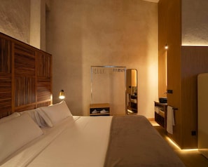 Una habitación de hotel con una cama, una mesita de noche, un espejo y un armario.