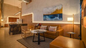 Een moderne hotelkamer met een kitchenette, een zithoek, een salontafel en een schilderij aan de muur.
