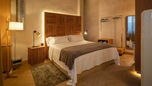 Een slaapkamer met een groot bed, een houten hoofdbord, nachtkastjes en een spiegel.