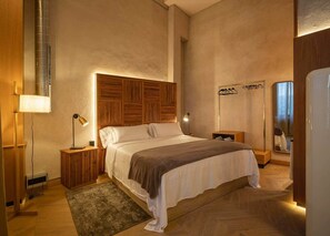 Un dormitorio con una cama grande, cabecera de madera, mesitas de noche y un espejo.