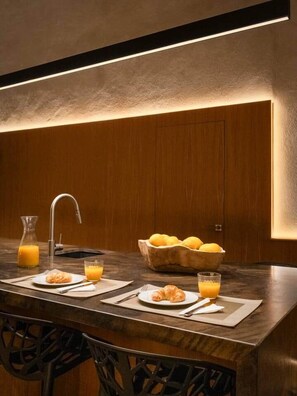 Una mesa de madera con dos platos de comida, un tazón de fruta y dos vasos de jugo de naranja.