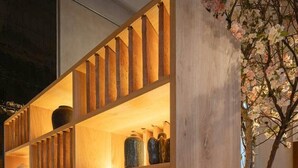 Een houten boekenkast met meerdere planken, waarvan sommige decoratieve objecten bevatten.