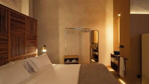 Habitación de hotel moderna con una cama grande, cabecero de madera, mesita de noche y un espejo.