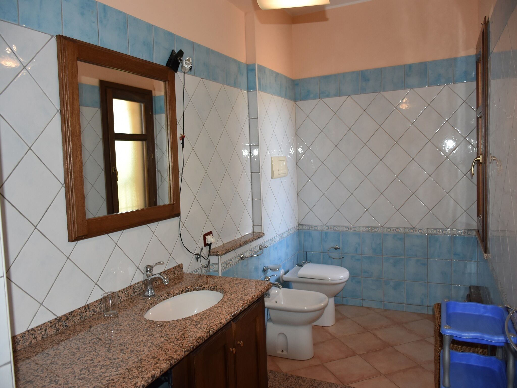 A bathroom with a sink, mirror, and two toilets.