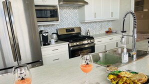 Una cucina moderna con elettrodomestici in acciaio inossidabile, mobili bianchi e un piano di lavoro in marmo.